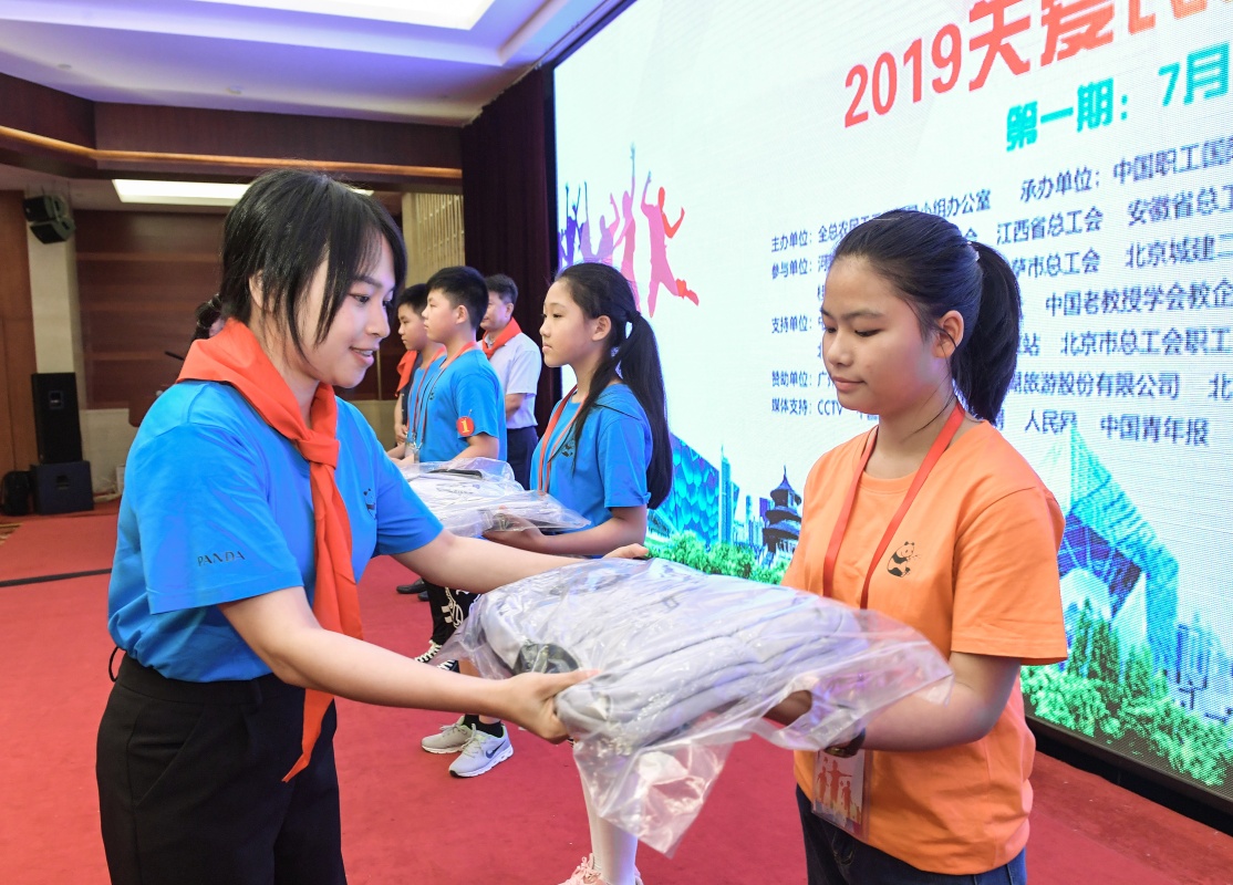 7月17日，开营仪式上爱心企业代表（左）向营员代表赠送服装和学习用品。新华社 李贺 摄